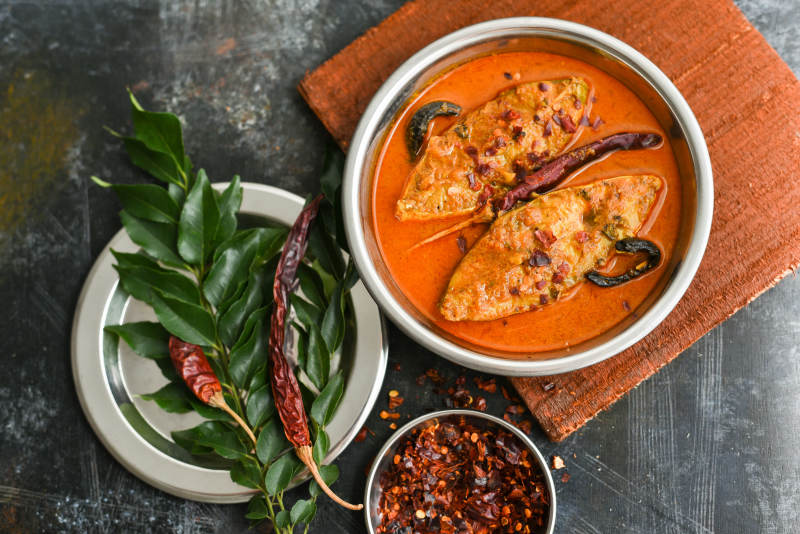 Top view of traditional Sri Lankan Fish Curry King fish curry, Sri Lanka on white background. Hot and spicy homemade yellow fish curry with gravy made using coconut milk , gambooge, turmeric